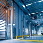 Spacious and modern warehouse interior with parked truck and steel structures.